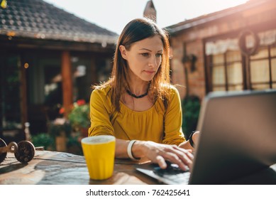 Women Wearing Yellow Shirt Using Laptop At Backyard Patio