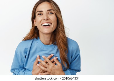 Women Wellbeing And Skin Care. Beautiful Middle Aged Woman Laughing, Holding Hands On Chest And Smiling Carefree, Standing In Blue Blouse Against White Background