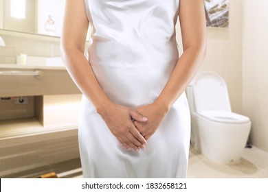 Women in a white dress want to urinating at the toilet. Peeing or urinary pain.