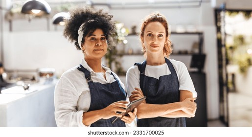 Women working as a team to manage a successful coffee shop business. Two female entrepreneurs wearing aprons in their cafe, ready to provide an excellent dining service for their customers. - Powered by Shutterstock