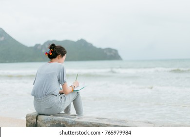 Women are writing on notebook at the beach