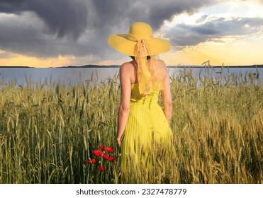  A women in a yellow dress in a field ,looks into the distance at the blossoming nature - Shutterstock ID 2327478779