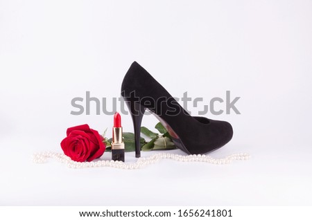 Women's accessories on a white background. Red rose, black stilettos, red lipstick, pearls