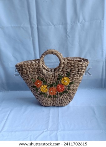 Women's bag made from woven water hyacinth with a beautiful flower motif in the middle.