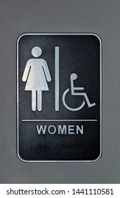 Women's Bathroom And Handicap Sign On A Wall. Depicts The Usage Of Braille At The Bottom Of The Sign.