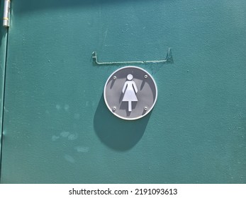 A Women's Bathroom Symbol On A Green Door.