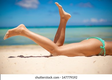 Women's Beautiful Smooth Legs On White Sand Beach