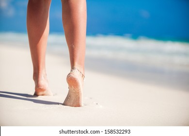 Women's Beautiful Smooth Legs On White Sand Beach