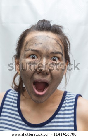 Women's black soap. Beautiful young girl wash her face with black soap on a white background and funny poses on the camera