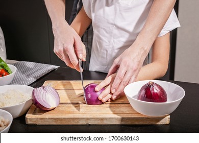 Women's And Children's Hands Cut Red Onions Together. Cooking With Kids Is Tasty In The Restaurant