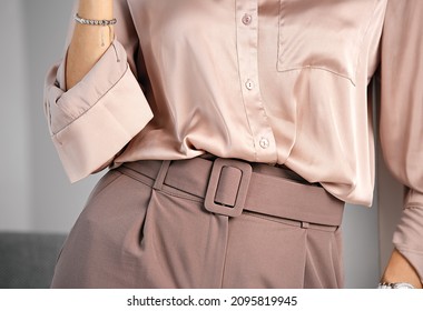 Women's classic business style of clothing. Palazzo trousers with a wide belt and a silk blouse. Powdery pink color. A combination of shades of color in clothing.
