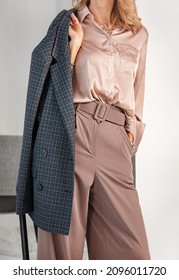 Women's classic business style of clothing. Palazzo trousers with a wide belt, silk blouse and jacket. Powdery pink color. A harmonious combination of shades of color in clothing. - Shutterstock ID 2096011720