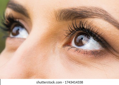 Women's eyes close up. The reflection in the pupils shows the silhouette of a man on a background of sky. Sunset.