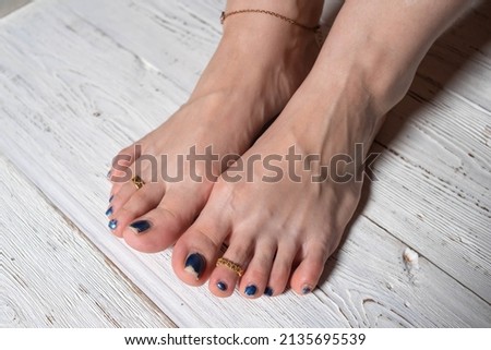 women's feet with blue lacquer on the toes on a white wooden background