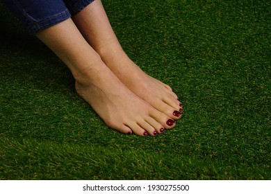 women's feet in grass with blue jeans