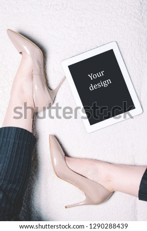 Women's feet in high heel shoes and a tablet pc. Template for design or apps