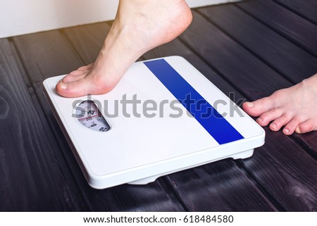 Women's feet are on mechanical scales for weight control on wooden background. The concept of slimming and weight loss