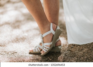 Women's Feet In White Sandals. Summer Outdoors