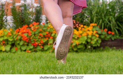 women's feet in white sneakers on the grass on the lawn against the background of blurred flowers. close-up. - Shutterstock ID 2193232137