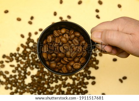 
In women's fingers, a cup with sprinkled coffee beans. Morning coffee concept