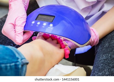 Women's Foot With A Lamp For Pedicure Close-up. The Manicurist Keeps The Led UV Lamp To Dry The Gel Nails.