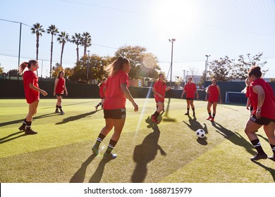 Womens Football Team Kicking Ball Whilst Training For Soccer Match On Outdoor Astro Turf Pitch