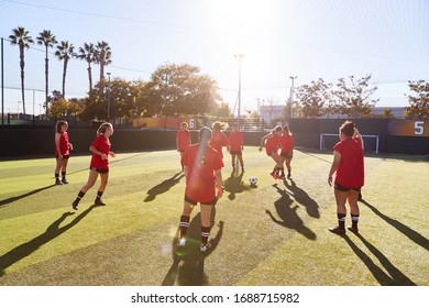 Womens Football Team Kicking Ball Whilst Training For Soccer Match On Outdoor Astro Turf Pitch