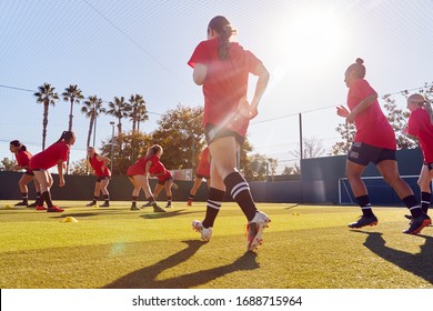 Womens Football Team Run Whilst Training For Soccer Match On Outdoor Astro Turf Pitch