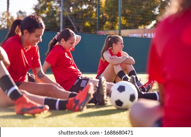 Womens Football Team Stretching Whilst Training For Soccer Match On Outdoor Astro Turf Pitch