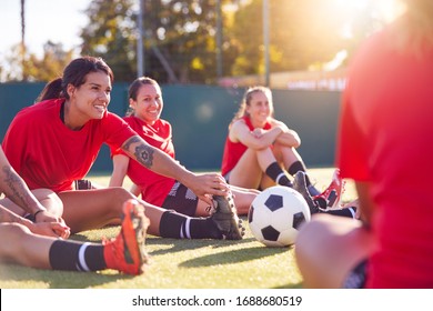 Womens Football Team Stretching Whilst Training For Soccer Match On Outdoor Astro Turf Pitch - Powered by Shutterstock