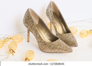 Womens Gold Chunky Glitter Pumps. Shoes For Wedding, Christmas, New Year, Evening, Cocktail, Night Out. Golden Stiletto Heels. Flat Lay. Footwear On White Wooden Background With Copy Space
