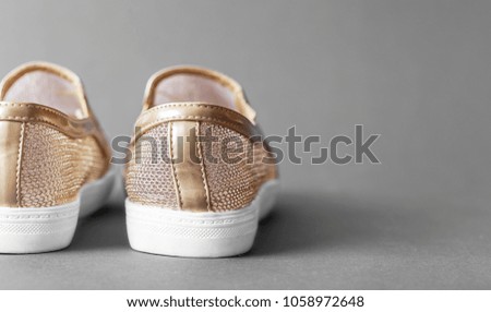 Women's golden moccasins close up. Lightweight comfortable summer shoes on a gray background.