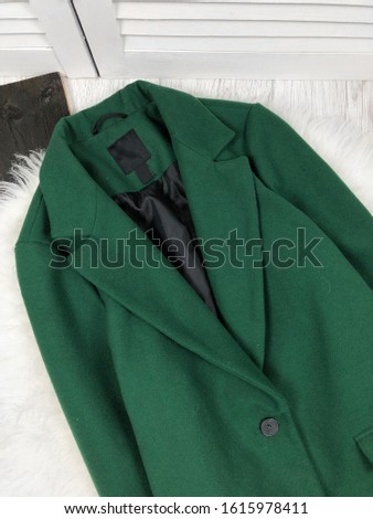 Women's green single-breasted coat in a large plan on a wooden background