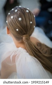 Women's Hair Is A Natural Blonde Hue Collected In A Pony Tail And Decorated With White Pearl