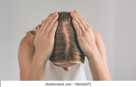 Women's hair is a top view close-up. Blonde woman is wearing shirt isolated on white.