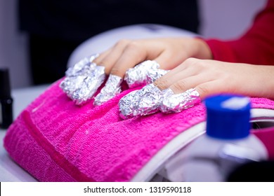 Women's Hand With Aluminum Foil On Nails On Pink Towel In Nail Salon.