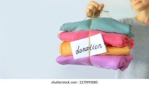 Women's hand give a stack of clothes to children's hands. Helping the poor, helping those in need. Clothes Donation, Renewable Concept. Preparing Garment at Home before Donate. Help from volunteers - Shutterstock ID 2170993085