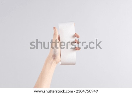 Women's hand hold white empty shopping receipt mockup on gray background. Template for design. Places for text