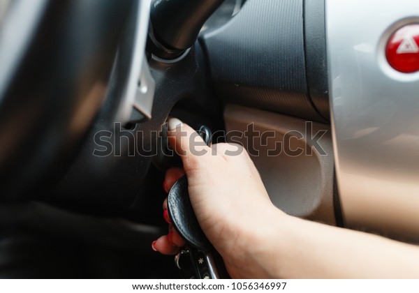 Women\'s hand turns the key to the car. Hands of\
the girl to take the keys to start the car engine. Key to start the\
car engine