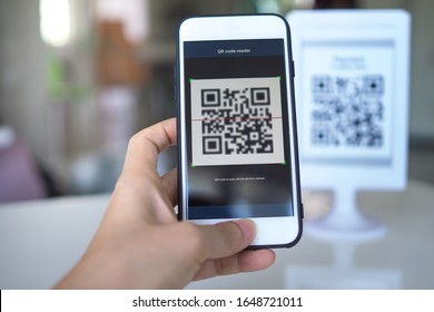 Women's hand использует приложение для мобильного телефона для сканирования QR-кодов в магазинах, которые принимают цифровые платежи без денег и пластиковых бирок на столе. Концепция оплаты QR-кода и наличных технологий
