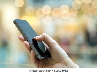 Womens hand using mobile phone on the bokeh background