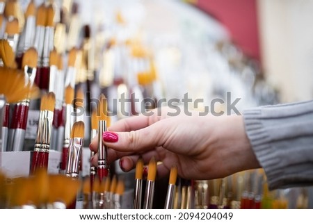 Women's hands choosing a paintbrush at the store
