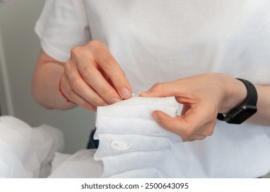 Women's hands in a close angle put hooks on the ribbon on the curtains.