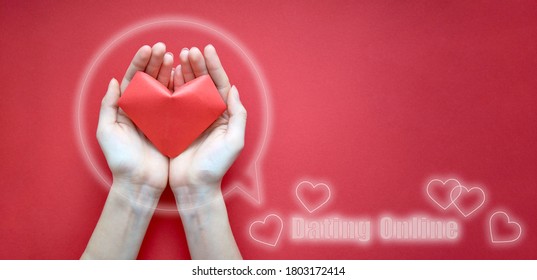 Women's hands are close-up holding a red paper heart inside the icon. Banner, copy space. The concept of online Dating. Ready-made template for the site - Powered by Shutterstock