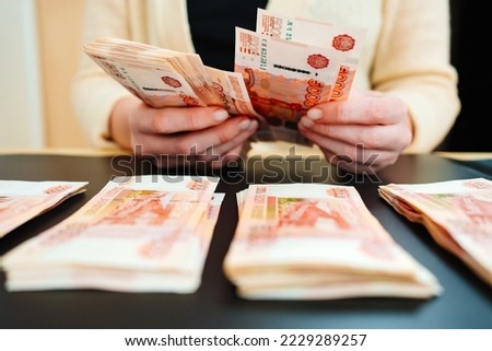 women's hands count a stack of money of a banknotes of 5000 rubles on a black background. the concept of depreciation of the ruble. earnings online in Russia.