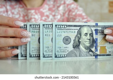 Women's hands are counting dollars in cash. 1000 dollars in 100 banknotes close-up.