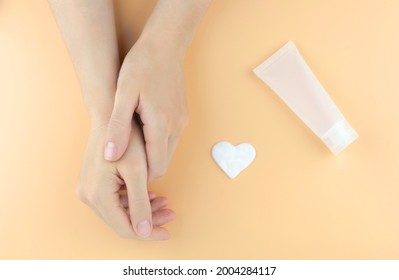 Women's Hands, Cream In The Shape Of A Heart And A Tube For Cream On A Beige Background. Mock Up Moisturizing Hand Cream.