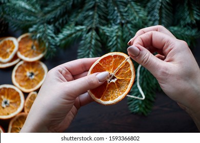 Women's Hands Create An Ornament For New Year And Christmas From Dried Orange, A Garland Of Natural Materials