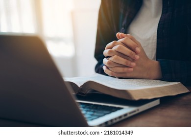 Women's Hands Are Folded In Prayer On A Holy Bible Over A Laptop In Church Concept For Faith, Religion, Love, And Forgiveness. Holy Bible Study Reading Together In Sunday School.Online Church