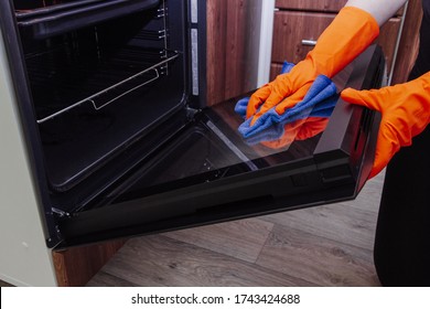 Women's Hands In Gloves With A Microfiber Cleaning Cloth Clean The Oven Door
